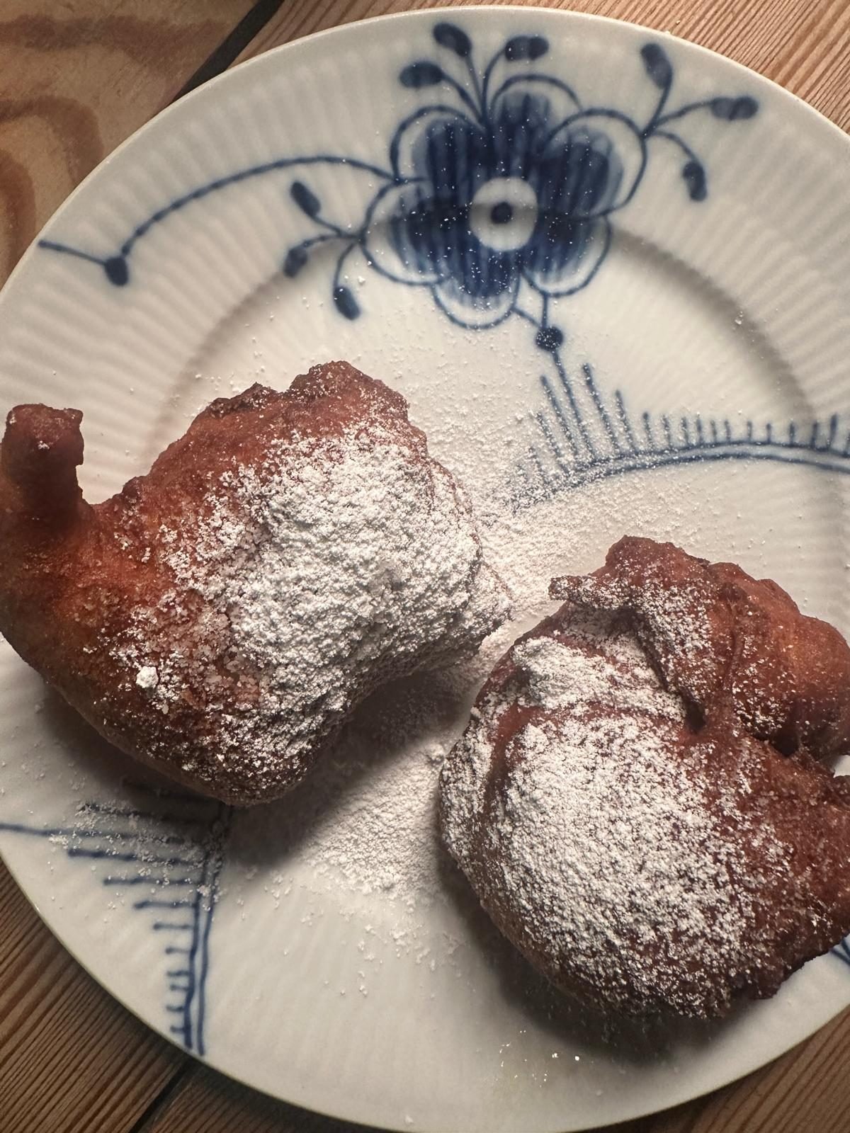 Zwei &AElig;r&oslash;-Pfannkuchen mit Puderzucker auf einem blau gemusterten Porzellanteller